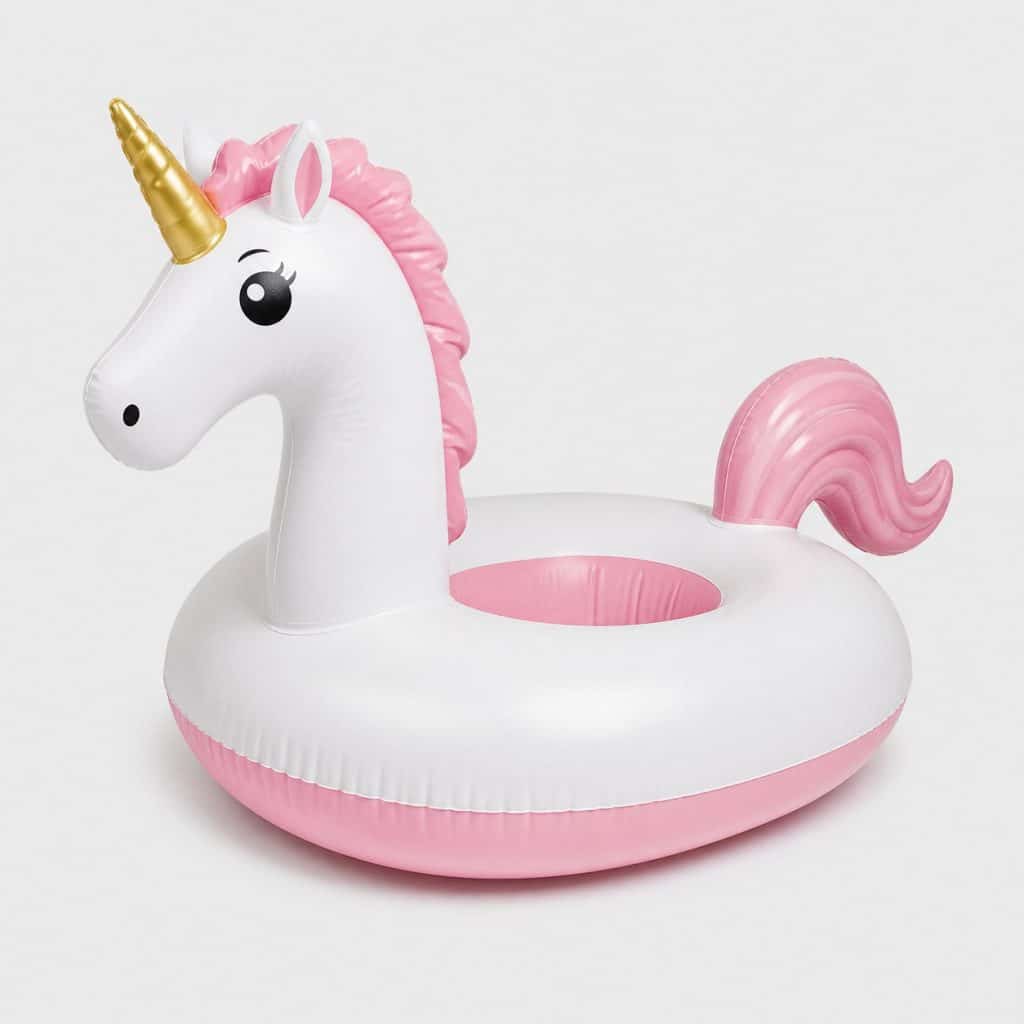 Bouée gonflable licorne blanc et rose posée sur fond clair