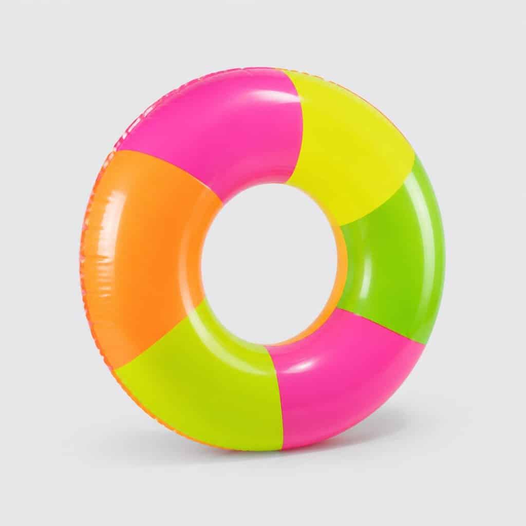 Bouée gonflable ronde aux couleurs néon vives posée sur fond clair