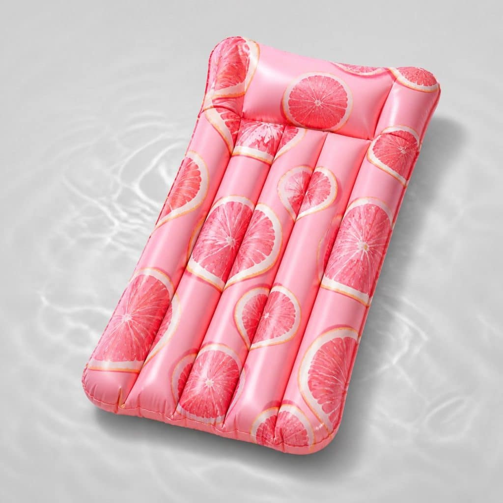 Matelas gonflable rose à motif pamplemousse vu de dessus sur l'eau